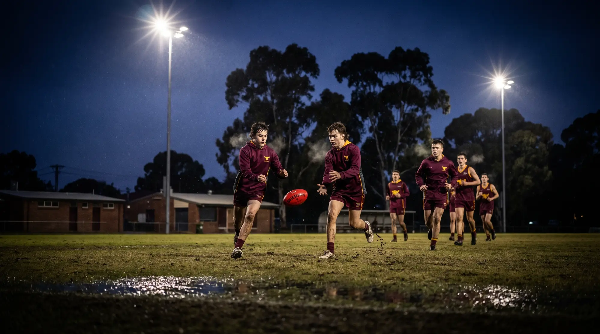 Junior footballers training under lights in the rain